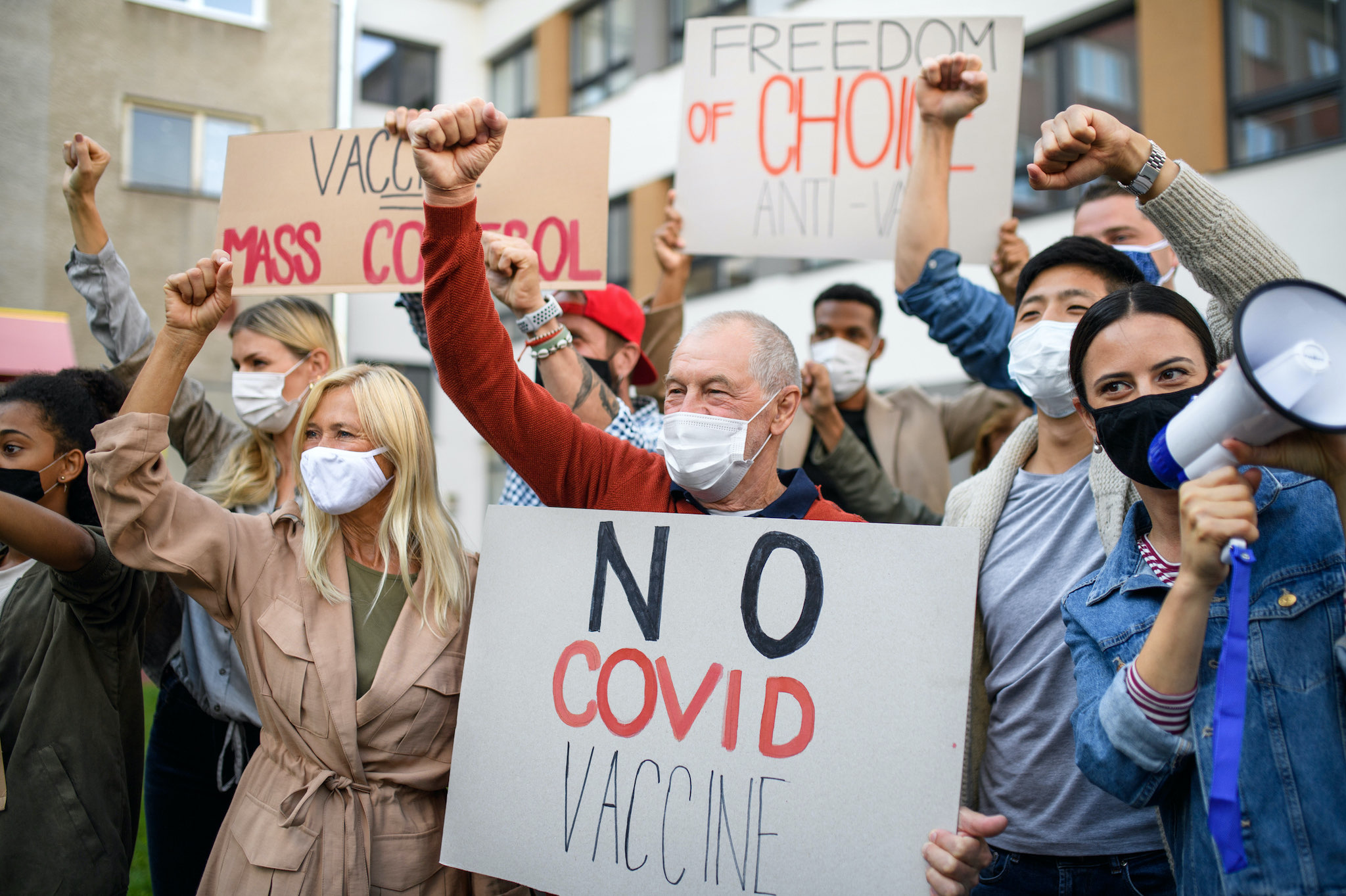 Crowd of people with placards and posters on public demonstration, no covid vaccine concept.