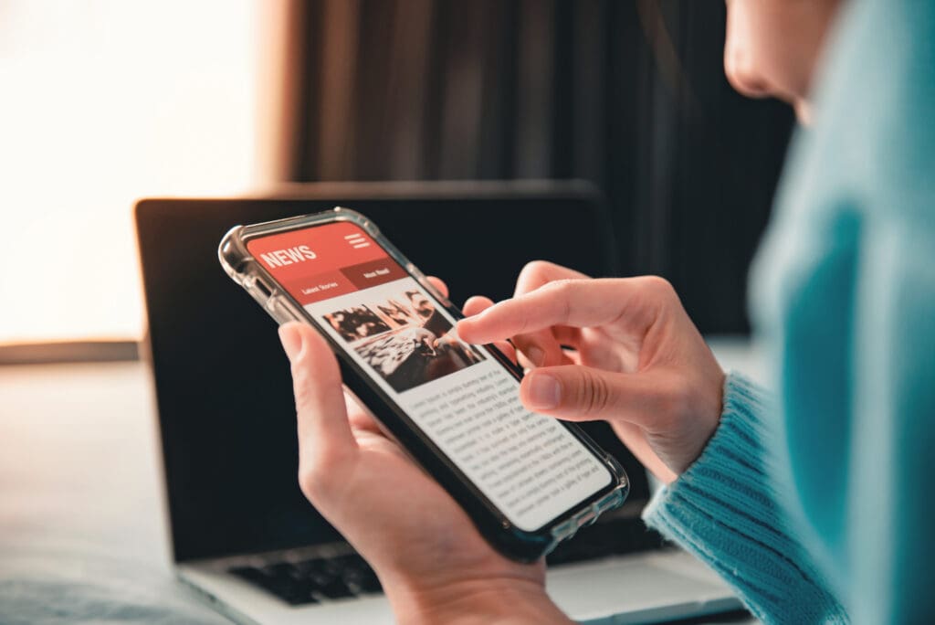 Online news on a smartphone, Woman reading news or articles in a mobile phone screen application at home. Newspaper and portal on internet.